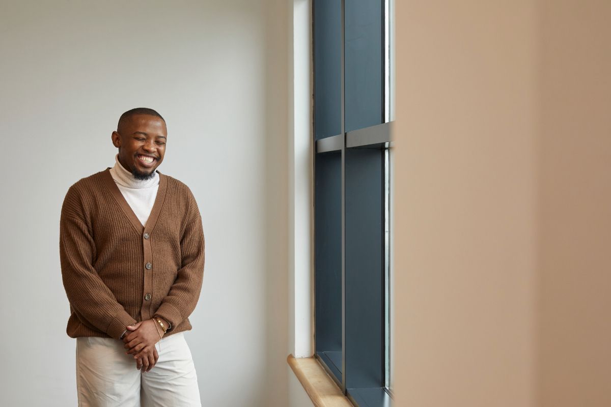 A Black male social worker in a bright local authority office, laughing.